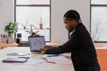 Small business owner focused on managing website and schedules on a laptop in a compact office.