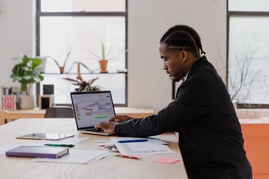 Small business owner focused on managing website and schedules on a laptop in a compact office.