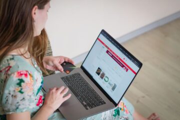 Small business owner using a laptop to manage online orders and payments in a home-shop setting.