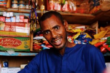 Local shopkeeper using tablet to manage stock and sales in a small retail store.