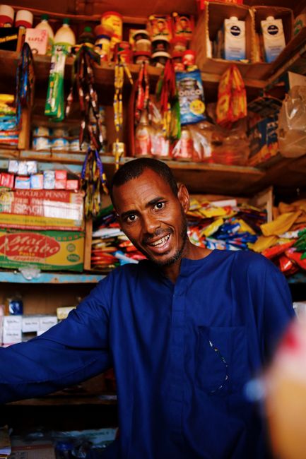 Local shopkeeper using tablet to manage stock and sales in a small retail store.