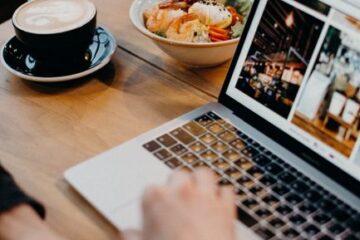Small business owner checking website on laptop inside shop.