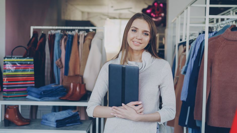 Retail boutique owner holding a tablet to manage inventory and online orders