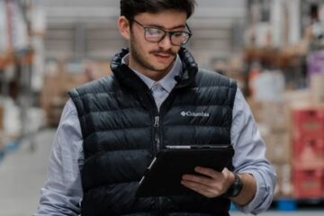 Warehouse worker using a tablet to check inventory in a small business warehouse.