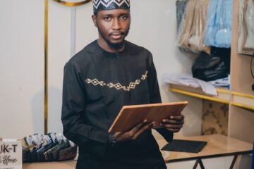 Local retail owner in a boutique holding a tablet to manage online orders and website analytics.
