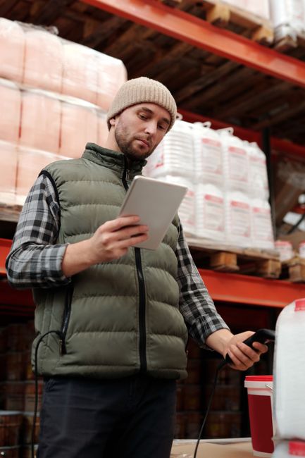 Warehouse employee using a tablet to check inventory in a small retail business.