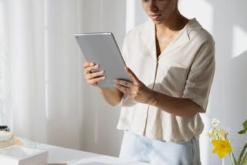 Small bakery owner using a tablet to manage orders and inventory in a bright kitchen shop.